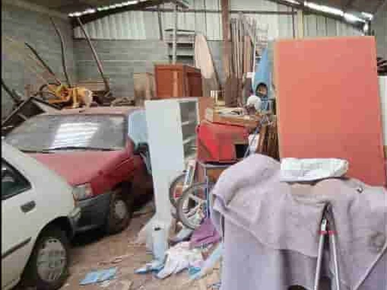 Hangar agricole encombré de véhicules, meubles et matériaux avant l'intervention